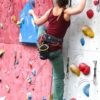 Mensch beim Klettern im Vorstieg in einer Kletterhalle kurz vor dem Clippen